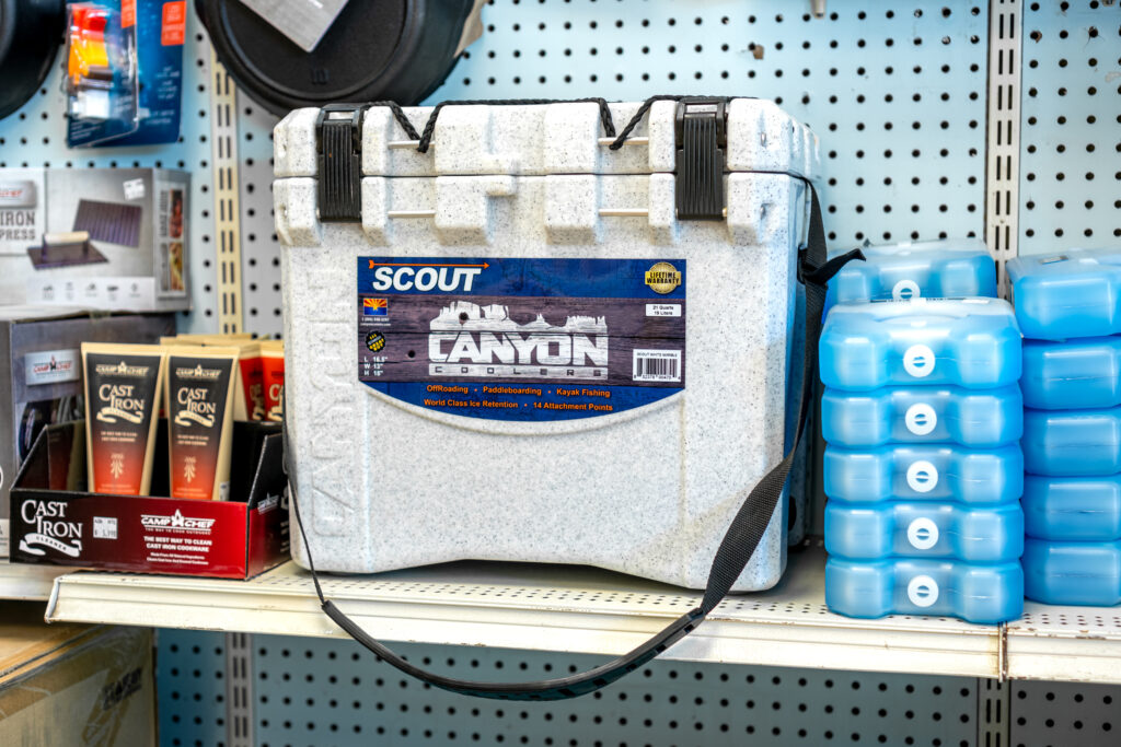 A cooler, icepacks, & cast iron cleaner all sat next to each other on a shelf.