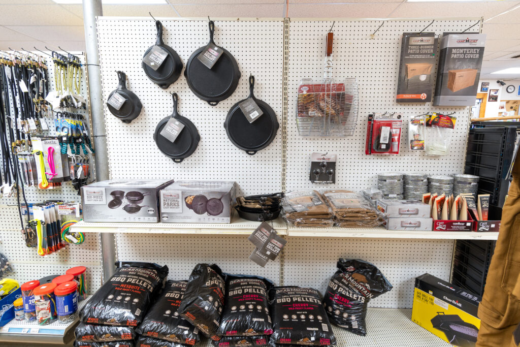 Various grill accessories sold at Four Star Supply, such as cast-iron pans & skillets, BBQ pellets, cast iron cleaner, and grill covers