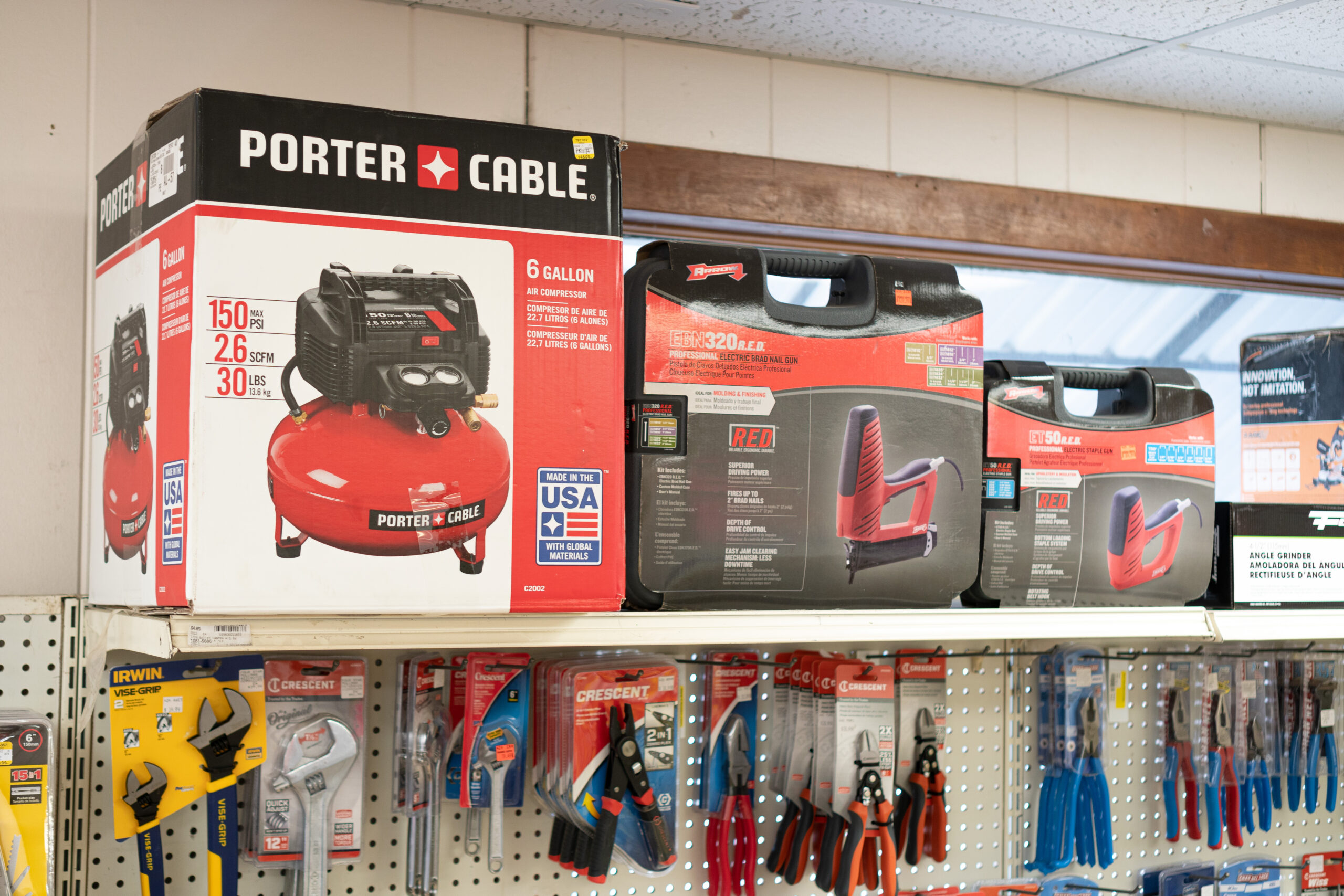 An Air Compressor and Nail Guns Sitting on a Shelf Above Wrenches & Pliers