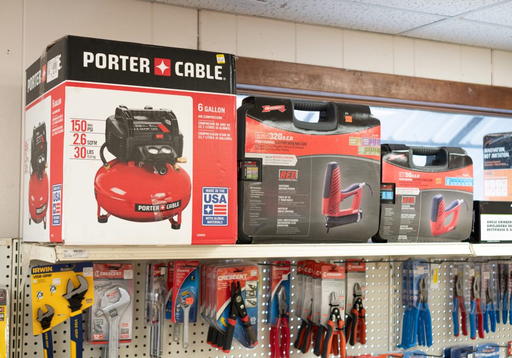 An Air Compressor and Nail Guns Sitting on a Shelf Above Wrenches & Pliers